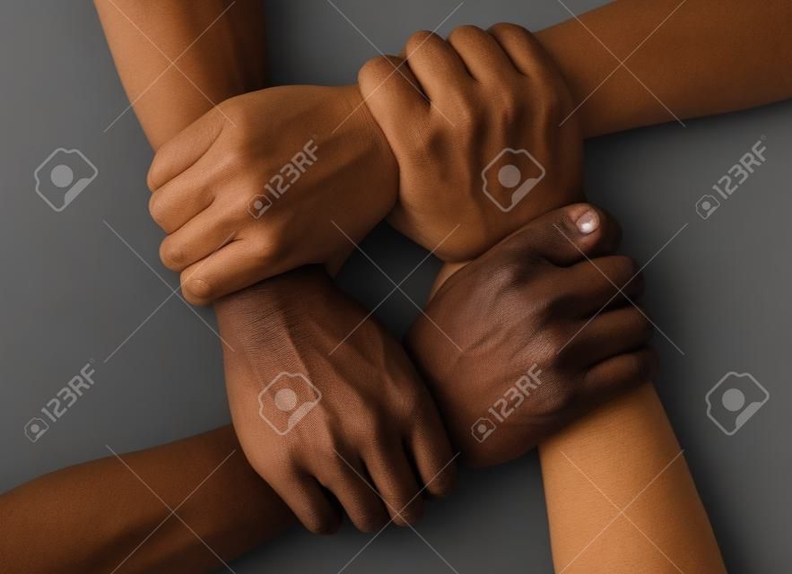 multiracial group with black african American Caucasian and Asian hands holding each other wrist in tolerance unity love and anti racism concept isolated on black background