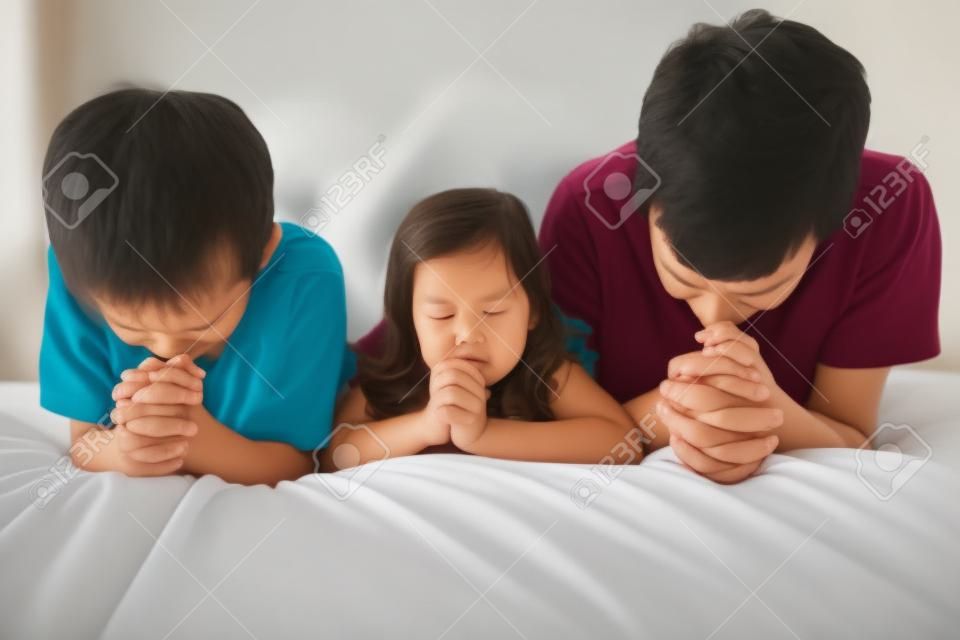 父母和孩子在床上祈禱