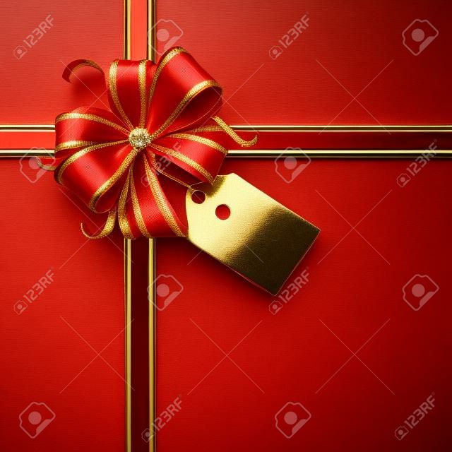 Rosso e fiocco regalo d'oro con un tag vuoto e nastri