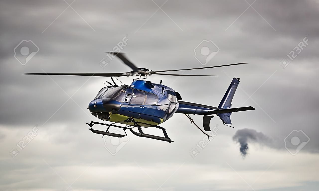 Blue helicopter in flight over a gray sky