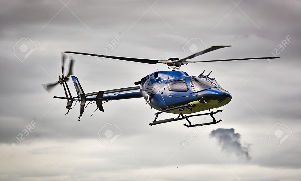 Blue helicopter in flight over a gray sky