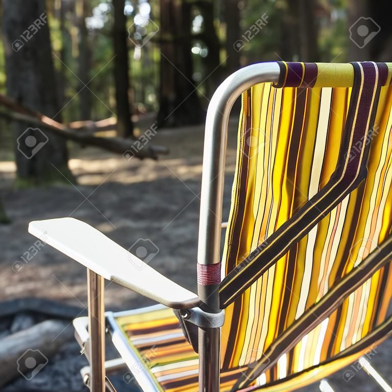 Retro fold up camping chair in front of the fire in the woods