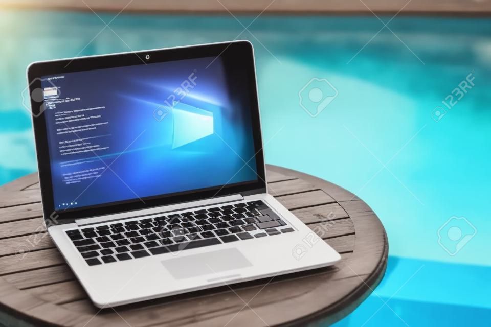 laptop em uma mesa de madeira contra o fundo da piscina aceita