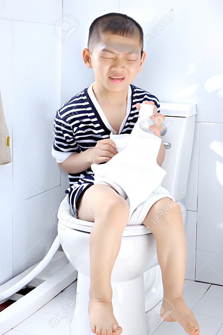 Young Asian Boy auf weißem WC in Toilette sitzen