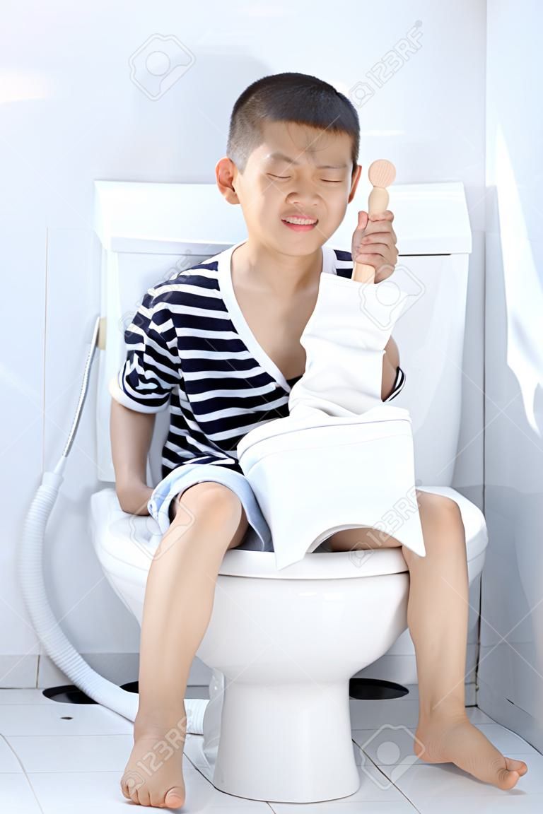 Young Asian Boy auf weißem WC in Toilette sitzen