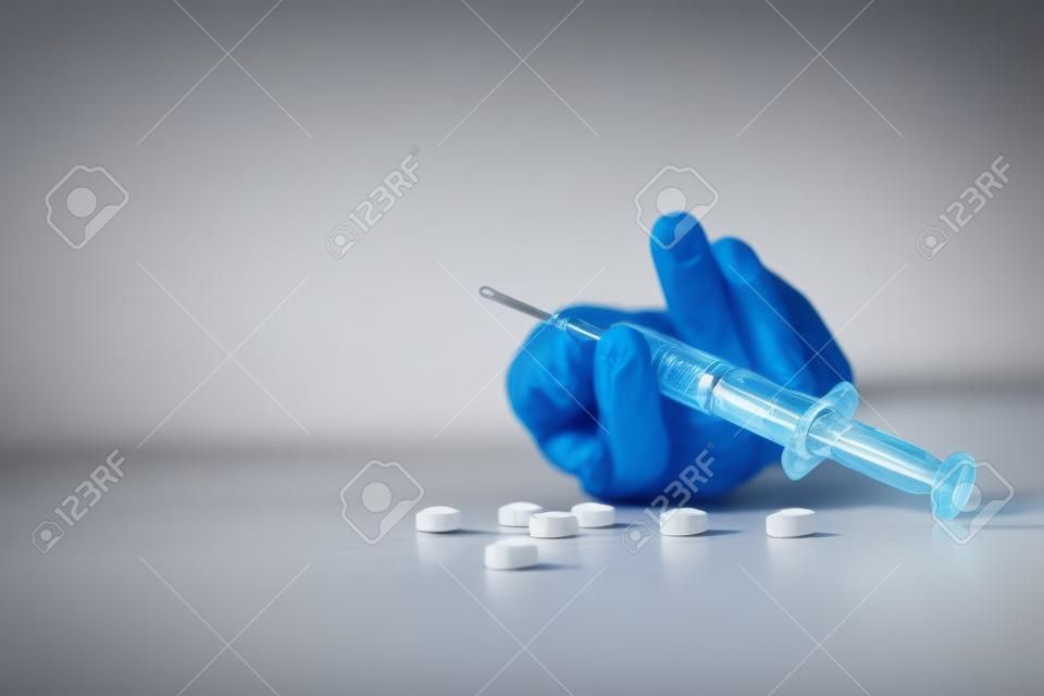 Woman hand of a drug addict and a syringe with narcotic syringe lying on the floor, Overdose, drug concept.