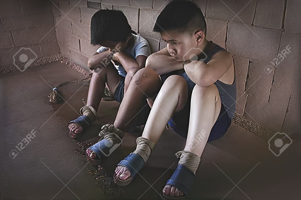 Two boys tied with rope. Abuse. Physical and mental abuse. Waiting for help. Violence against children.