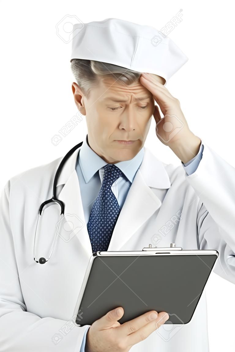 Confused mature male doctor looking at digital tablet isolated over white background
