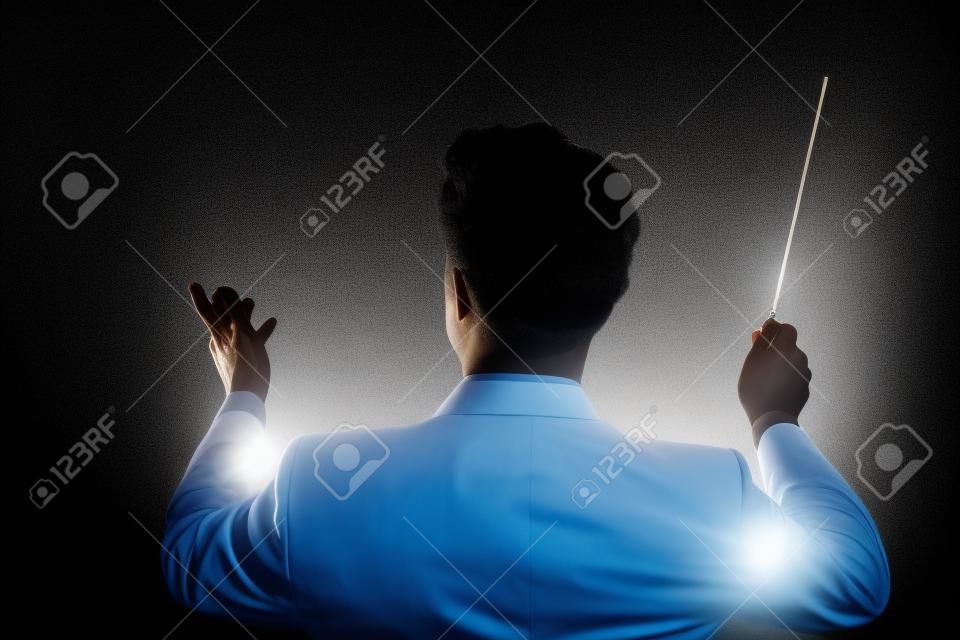 Vista traseira do maestro de música masculina dirigindo com seu bastão contra o fundo preto