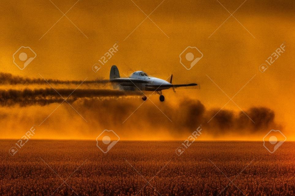 Crop duster, aircraft silhouette over tilled agricultural field.