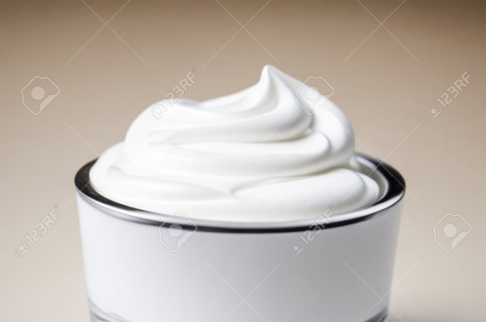 Draaien van gladde witte crème in een kleine glazen kom