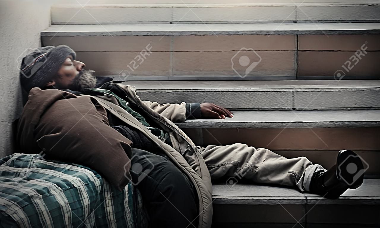Dirty homeless sleeping on stair with liquor bottle
