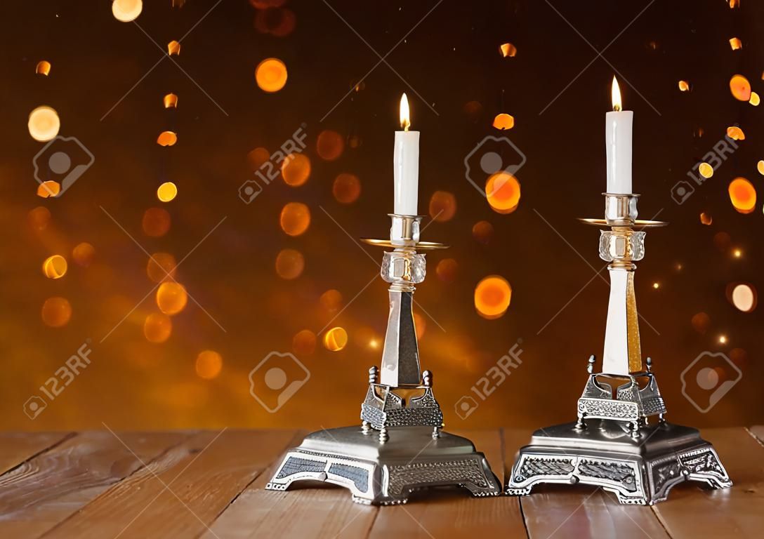 dos candelabros con velas encendidas sobre la mesa de madera y fondo del brillo de la vendimia