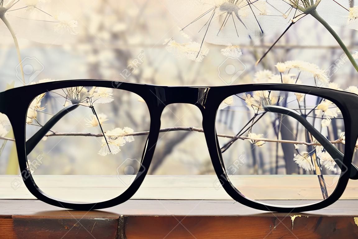 gafas hipster en una mesa rústica de madera delante de flores blancas