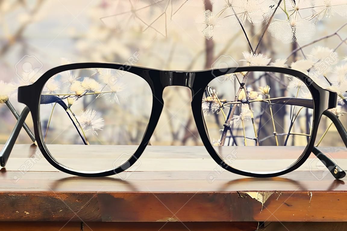 hipster glasses on a wooden rustic table in front of white flowers