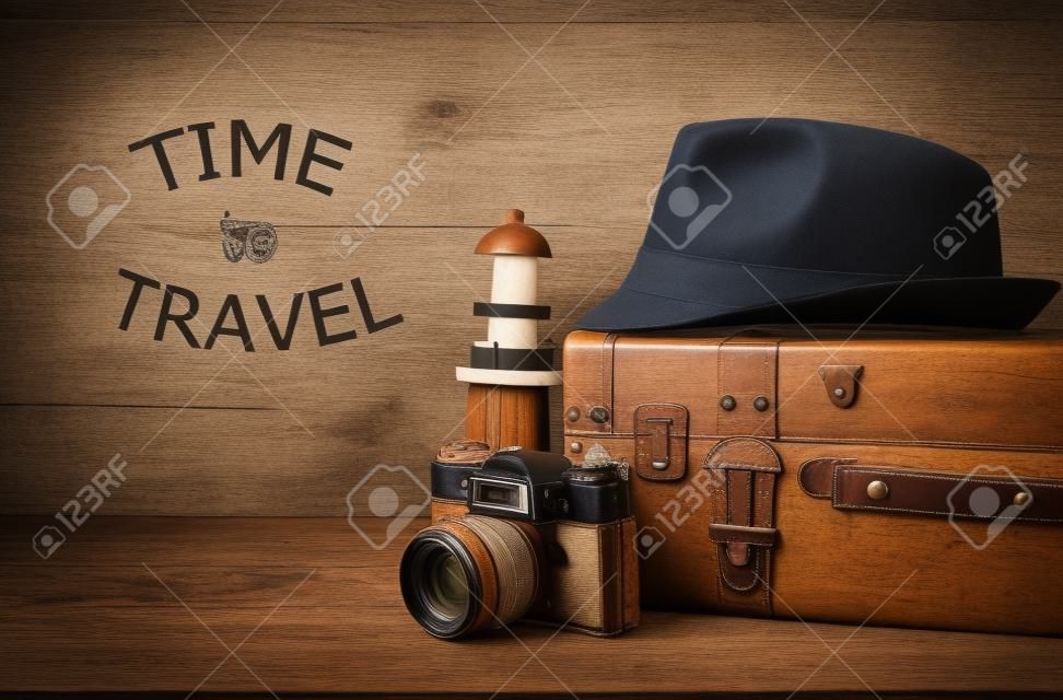 traveler vintage luggage, camera and fedora hat over wooden table. holiday and vacation concept