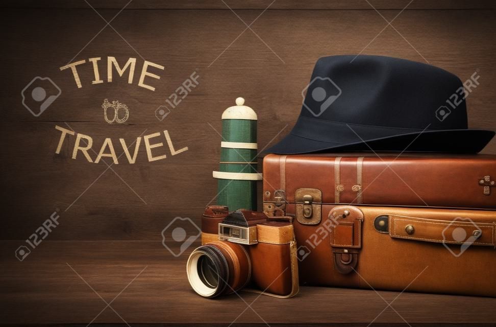 viajero vintage equipaje, cámara y sombrero fedora sobre mesa de madera. concepto de vacaciones y vacaciones