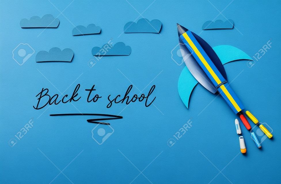 Concepto de regreso a la escuela. cohete, formas de elementos espaciales cortadas de papel y pintadas sobre fondo azul de madera