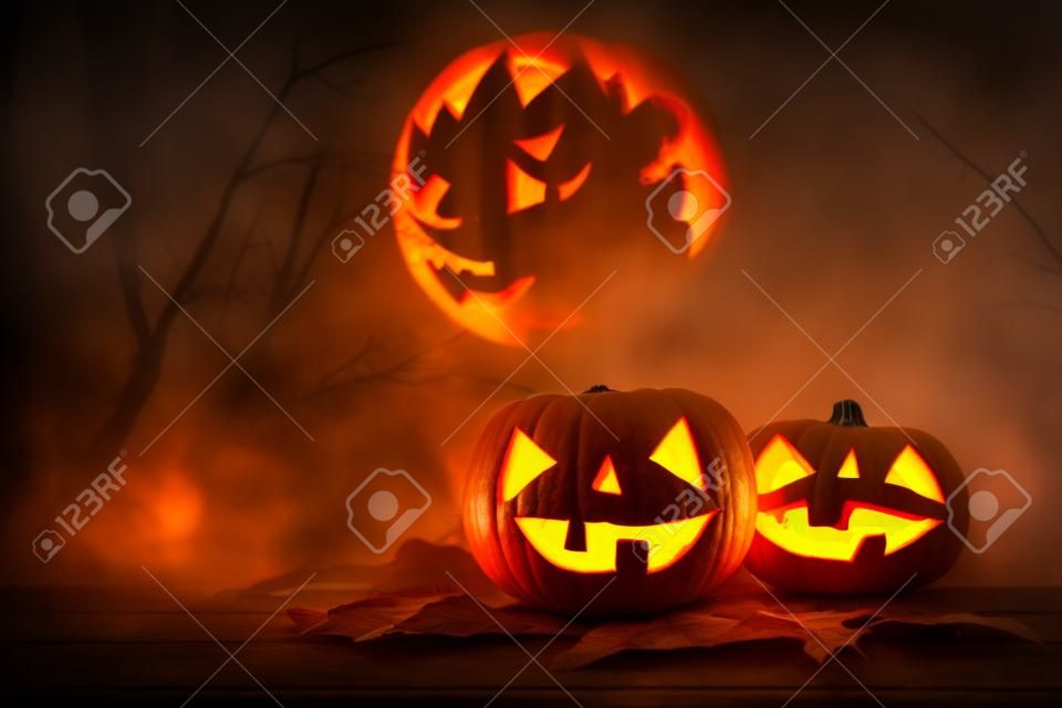 Halloween holiday concept. Pumpkins over wooden table at night scary, haunted and misty forest