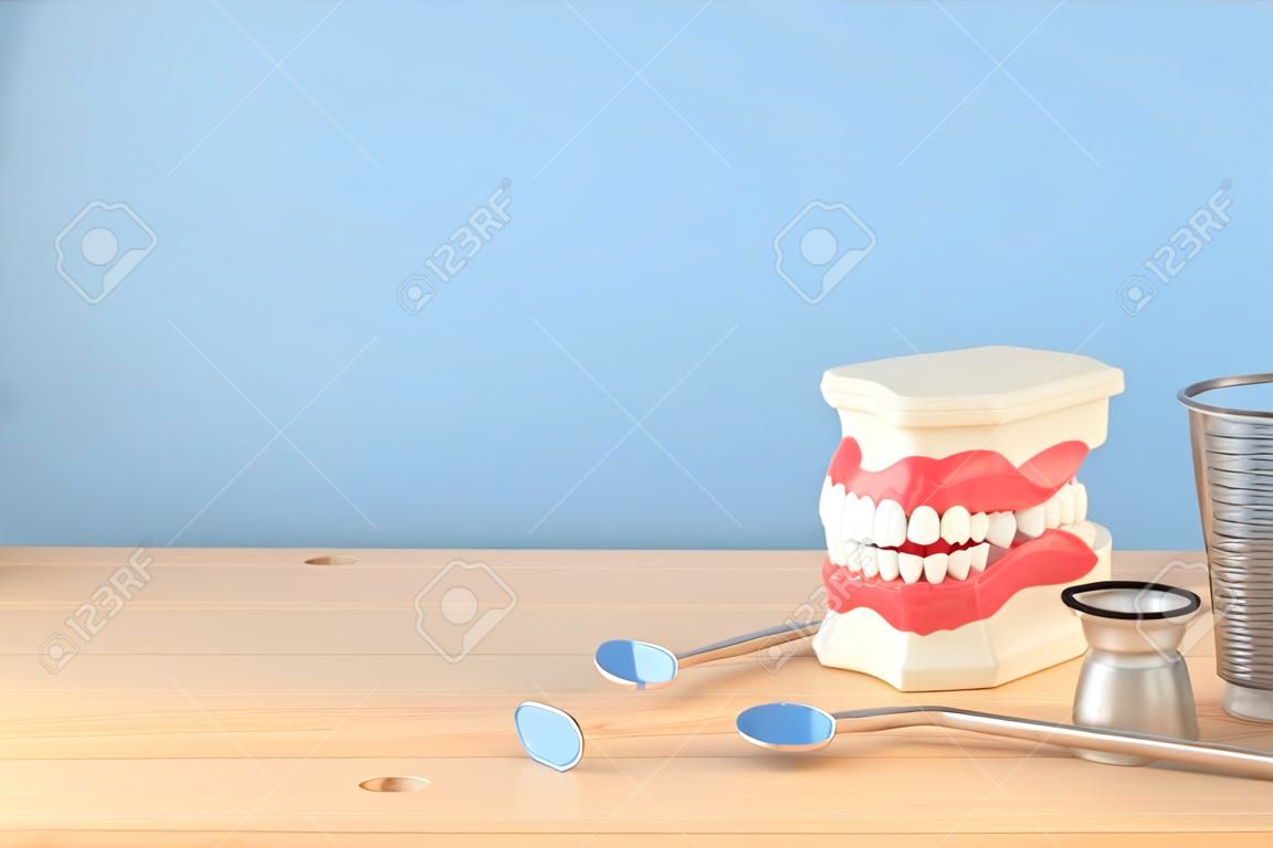 치과 치료 도구는 클리닉의 치과 의사 및 플라스틱 치아 모델에 사용됩니다. 나무 파란색 배경