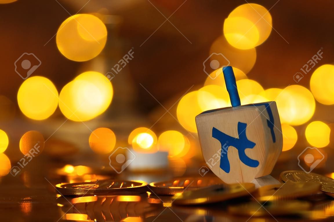religion concept of of jewish holiday Hanukkah with wooden dreidels (spinning top) and chocolate coins over wooden table and bokeh lights background