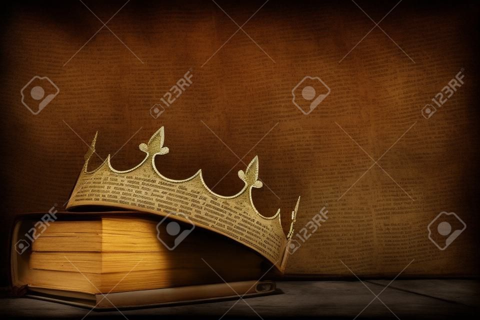 immagine chiave bassa della bellissima corona regina/re su un vecchio libro e un tavolo di legno. annata filtrata. periodo medievale fantasy