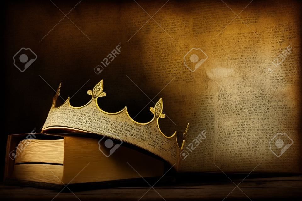 immagine chiave bassa della bellissima corona regina/re su un vecchio libro e un tavolo di legno. annata filtrata. periodo medievale fantasy