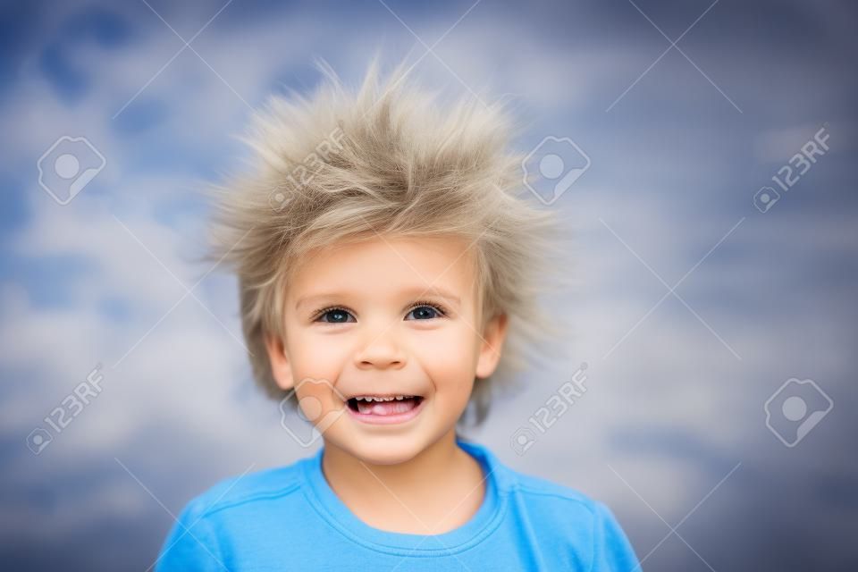 Netter kleiner Junge mit statischem elektrischem Haar, sein lustiges Porträt draußen auf einem Trampolin genommen