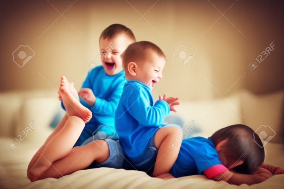Dzieci, bracia, bawiące się w domu, łaskoczące stopy śmiejące się i uśmiechnięte
