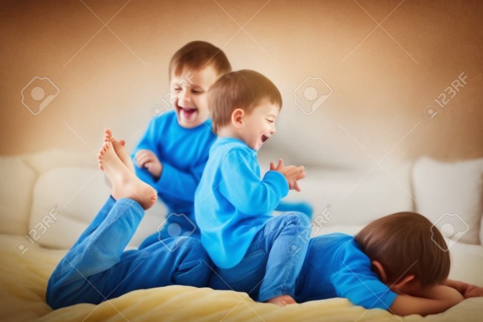 Niños, hermanos, jugando en casa, haciendo cosquillas en los pies, riendo y sonriendo