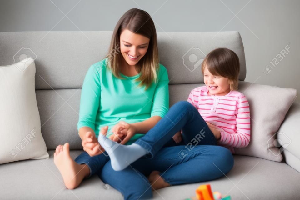 Mother, tickling her little boy, child giggling at home with mom in living room
