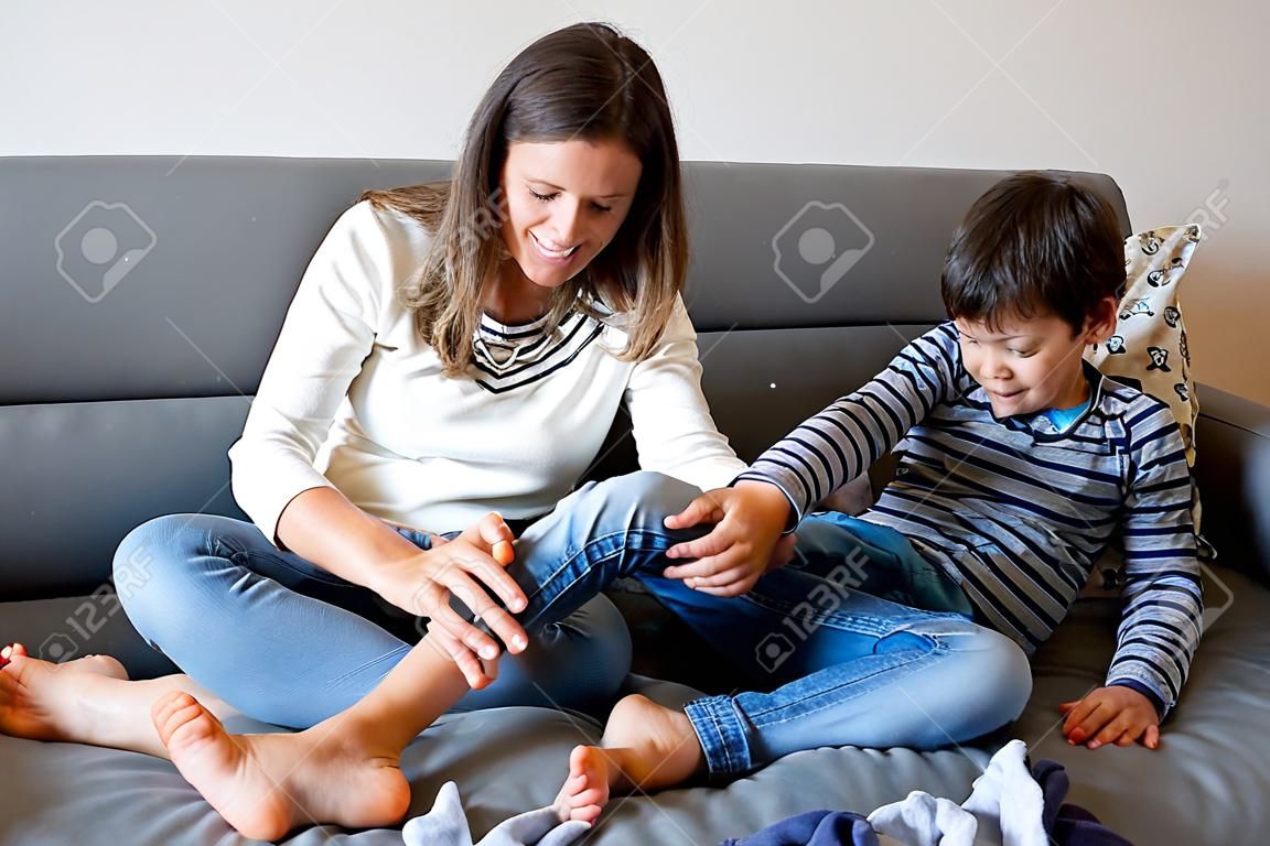Mère, chatouillant son petit garçon, enfant riant à la maison avec maman dans le salon