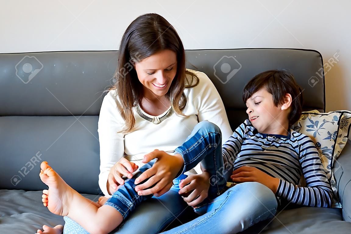 Matka łaskocząca swojego synka, chichoczące dziecko w domu z mamą w salonie
