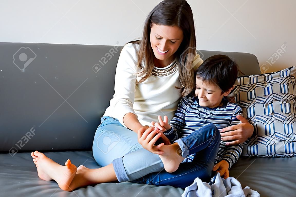 Matka łaskocząca swojego synka, chichoczące dziecko w domu z mamą w salonie