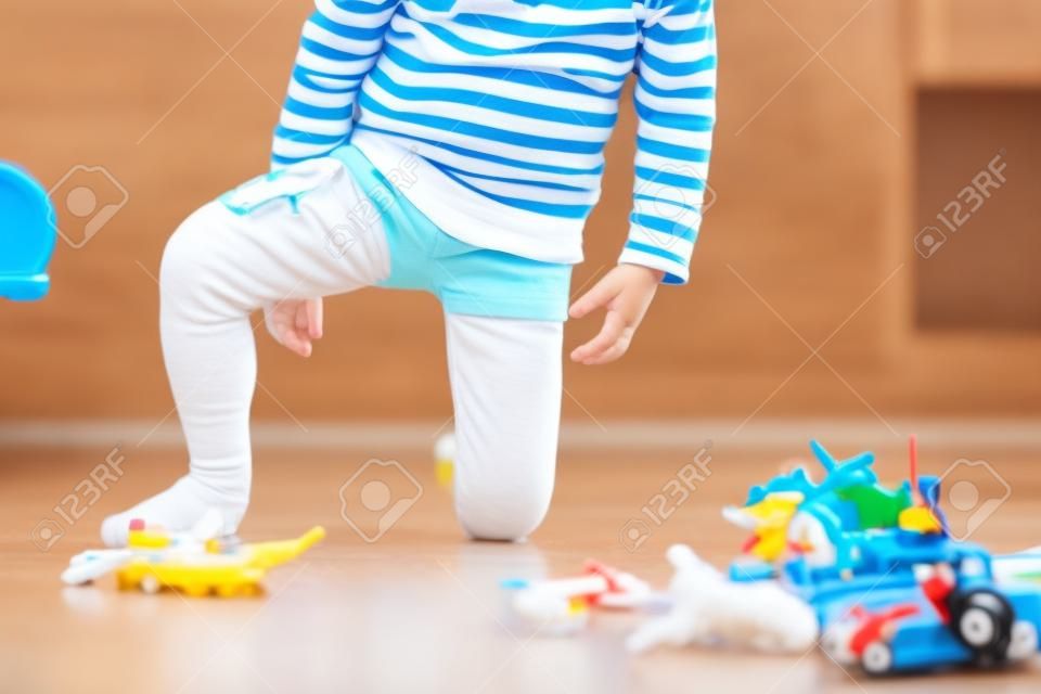 Małe dziecko, chłopiec, sika w spodnie podczas zabawy zabawkami, dziecko jest rozproszone i zapomina iść do toalety w domu