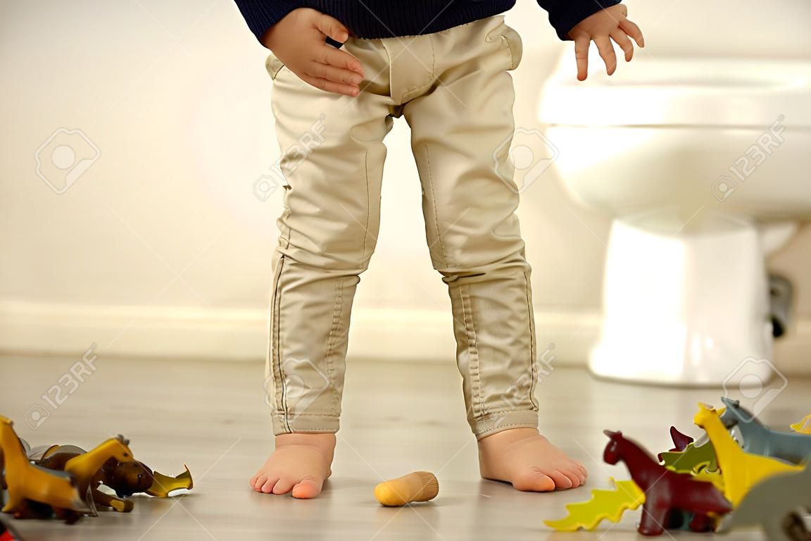 Petit enfant en bas âge, garçon, fait pipi dans son pantalon en jouant avec des jouets, enfant distrait et oublie d'aller aux toilettes à la maison