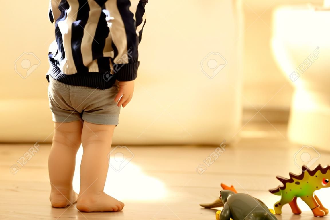 Petit enfant en bas âge, garçon, fait pipi dans son pantalon en jouant avec des jouets, enfant distrait et oublie d'aller aux toilettes à la maison