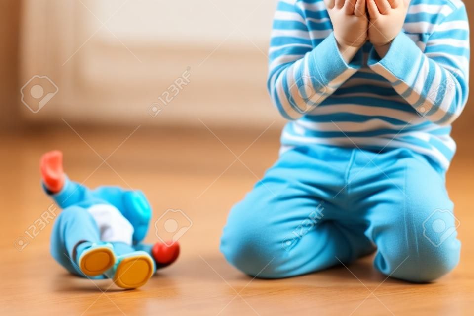 Criança pequena, menino, fazer xixi em suas calças enquanto brinca com brinquedos, criança distraída e esquecer de ir ao banheiro em casa