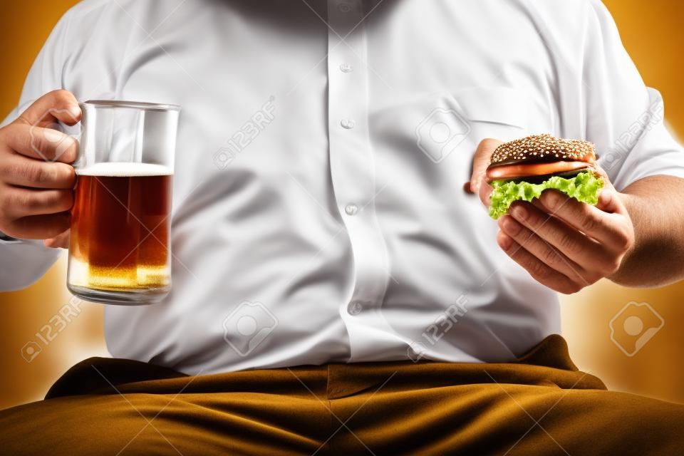 grasso uomo d'affari azienda boccale di birra e hamburger