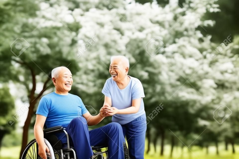 Hombre mayor asiática que se sienta en una silla de ruedas con su esposa