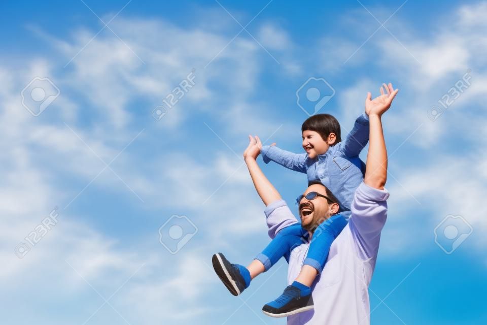 快樂的父親背著女兒的肩膀上有藍色的天空背景