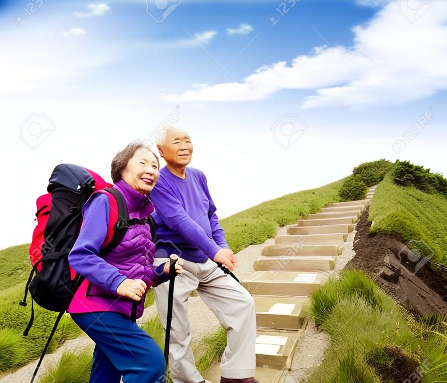 happy asian senior couple hiking on the mountain