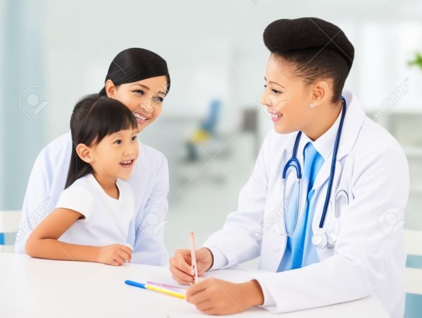 Młody lekarz mówi do małego dziecka i matki