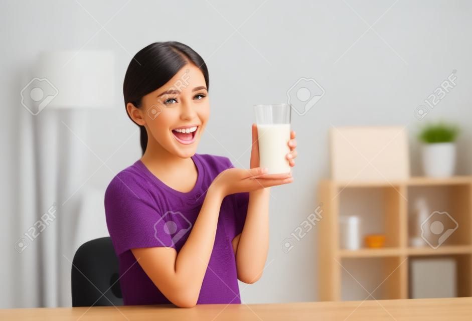 快樂的年輕女子喝牛奶