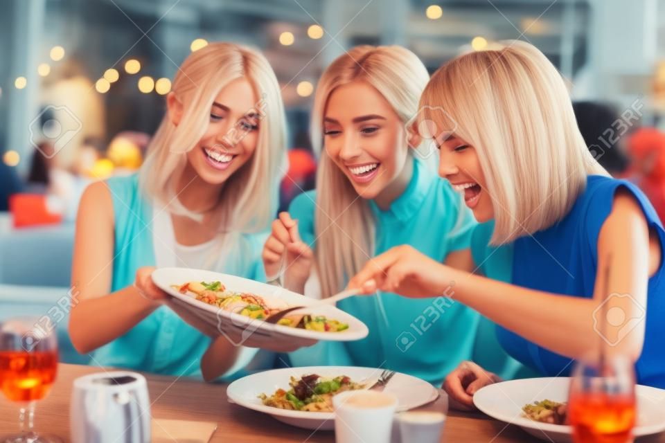 Grupa szczęśliwych przyjaciół jedzących obiad w restauracji?