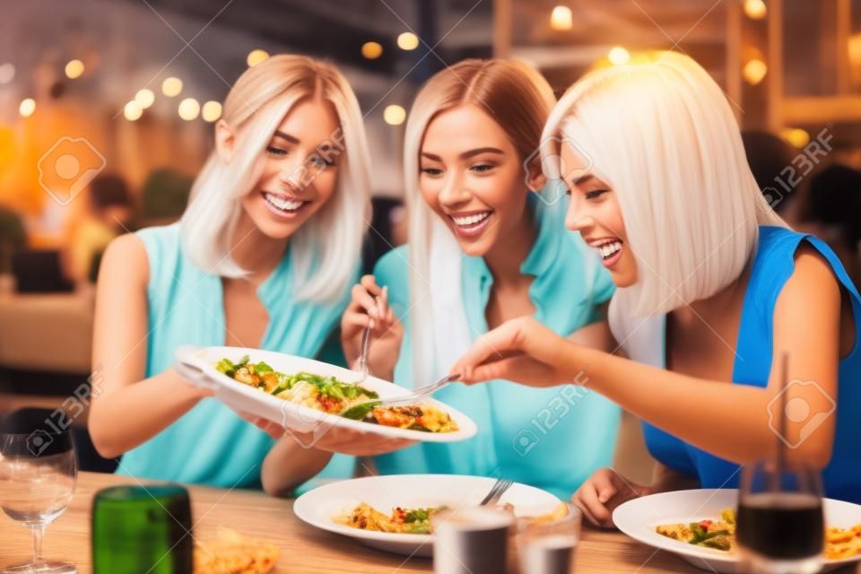 Grupa szczęśliwych przyjaciół jedzących obiad w restauracji?