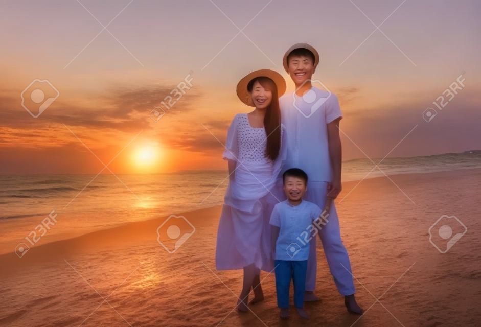 happy  asian family standing on the beach  at sunset