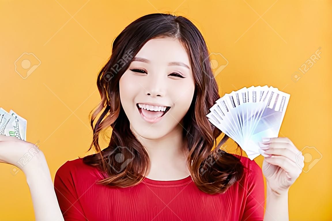 giovane donna felice che tiene soldi e carta di credito.