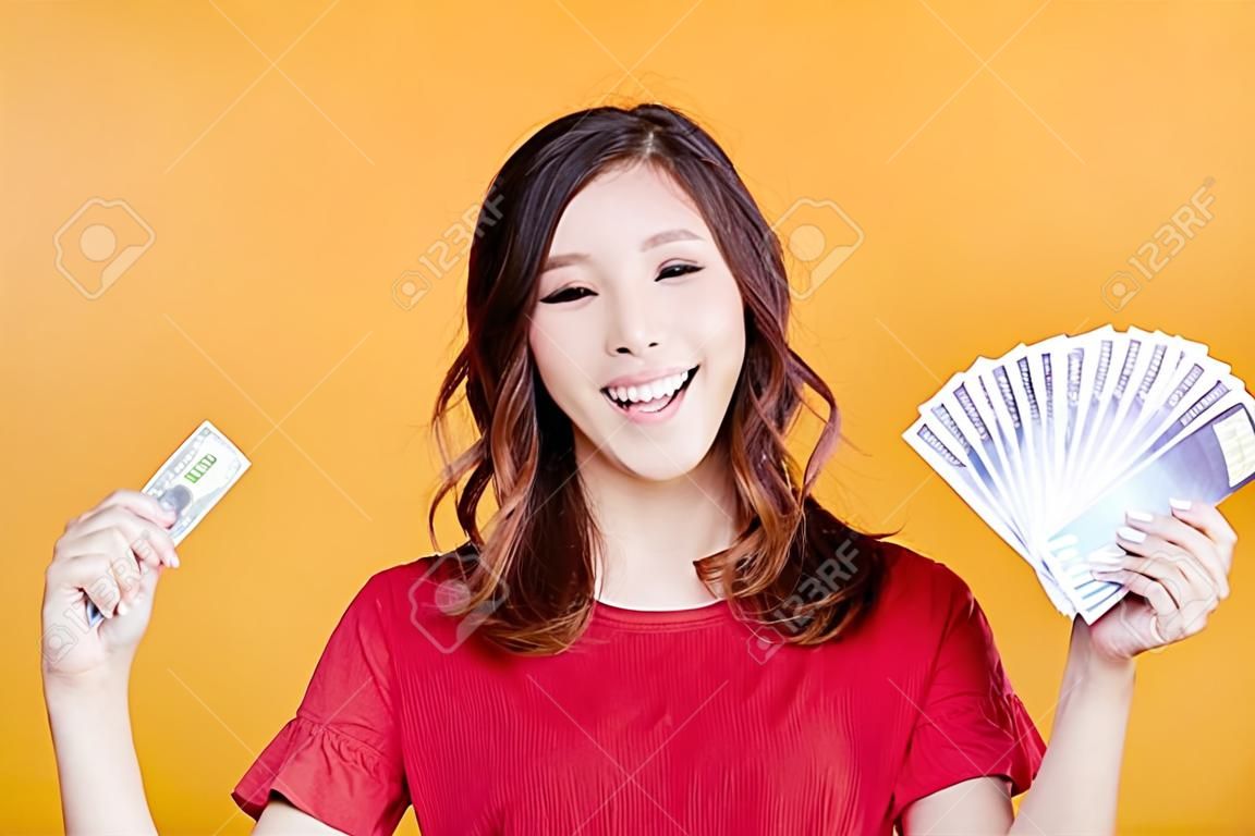 giovane donna felice che tiene soldi e carta di credito.