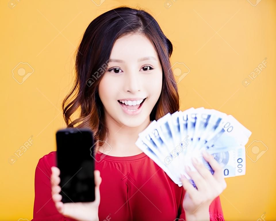 Gelukkige jonge vrouw met mobiele telefoon en geld.